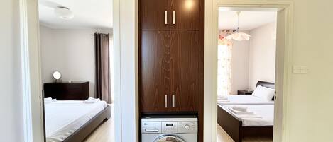 A compact hotel room with a bed, a washing machine, and a wardrobe.