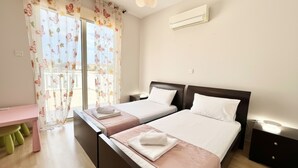 Un dormitorio con dos camas, un escritorio y una ventana con cortinas florales.