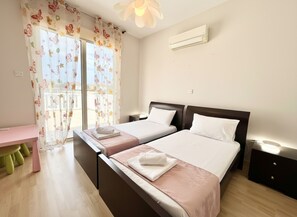 Un dormitorio con dos camas, un escritorio y una ventana con cortinas florales.