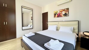 Habitación de hotel con cama, espejo grande, cuadro y armario.