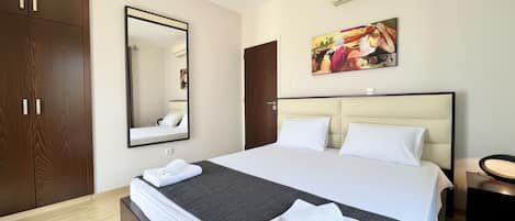 A hotel room with a bed, a large mirror, a painting, and a wardrobe.