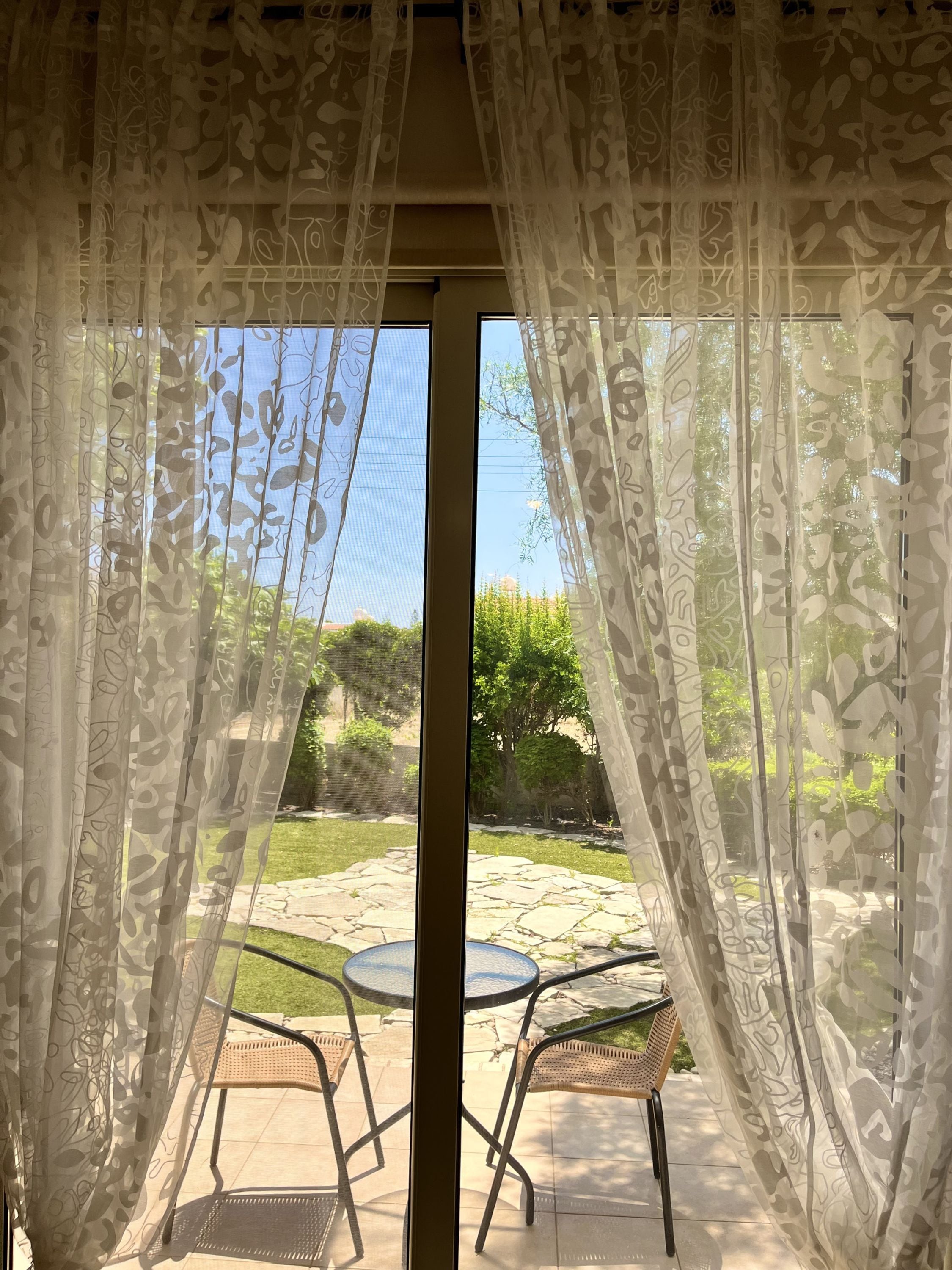 Un patio con mesa y sillas, un sendero de piedra y follaje.
