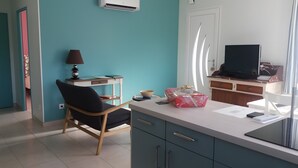 Una cuina moderna amb zona de menjador, televisió i finestra amb cortines.
