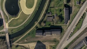An aerial view of a facility with multiple buildings, a large water body, and surrounding green areas. - "Les Pistes" Chalet (Ax-les-Thermes)