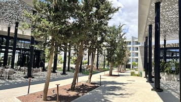 Uma área externa moderna com árvores, assentos e um edifício com teto estampado.
