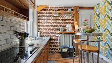 Une cuisine avec un mur en briques, des armoires en bois, un plan de travail en acier inoxydable et un coin bar avec des tabourets.