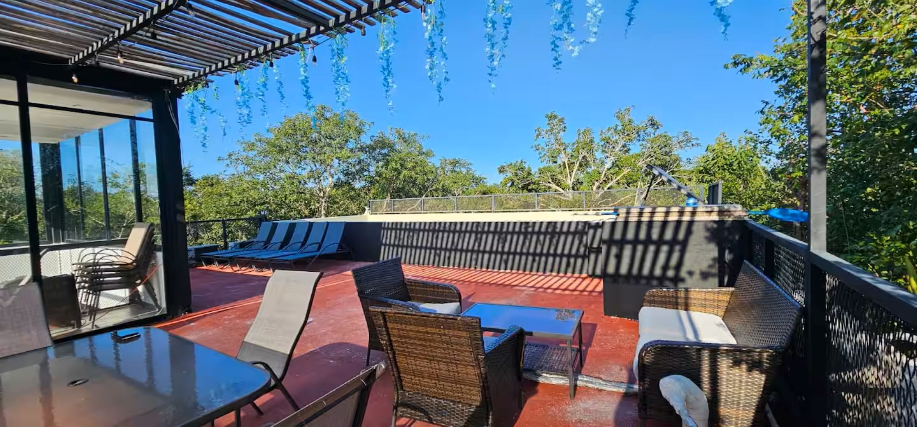 Une terrasse sur le toit avec des sièges extérieurs, une pergola et une vue sur les arbres.