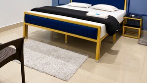 Un dormitorio con cama, mesita de noche, silla, ventilador de techo y unidad de aire acondicionado.