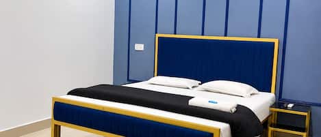 A bedroom with a bed, a bedside table, a chair, a ceiling fan, and an air conditioning unit.