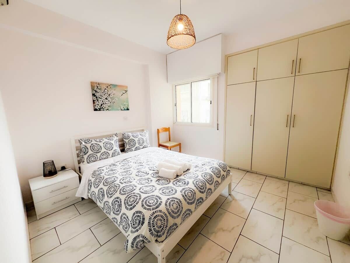 A bedroom with a bed, nightstand, wardrobe, and a hanging light fixture.