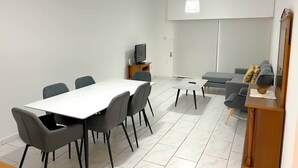 Ein modernes Wohnzimmer mit Esstisch, Stühlen, einer Couch und einem Fernsehmöbel.