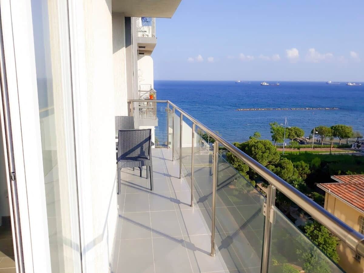 En balkon med udsigt over havet, en stol og et gelænder.