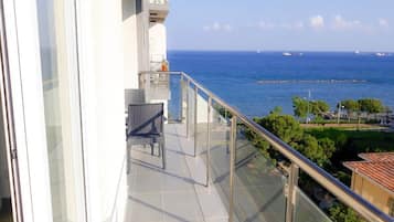 En balkon med udsigt over havet, en stol og et gelænder.