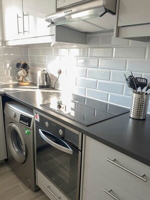 Une cuisine moderne dotée d’appareils électroménagers en acier inoxydable, d’un dosseret de carrelage blanc et d’un four encastré.