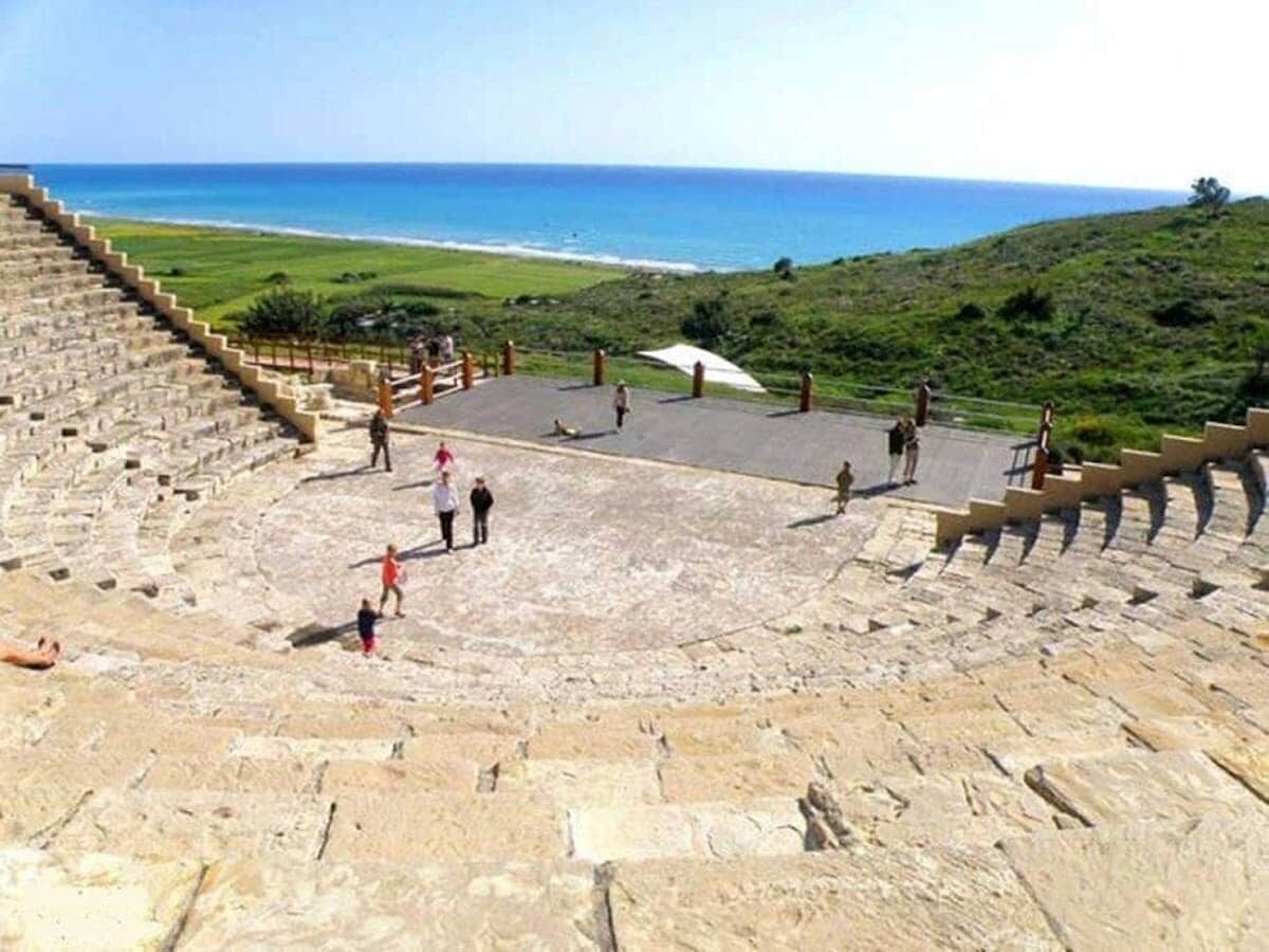 Un amphithéâtre antique avec des gradins en pierre et une vue sur l’océan.