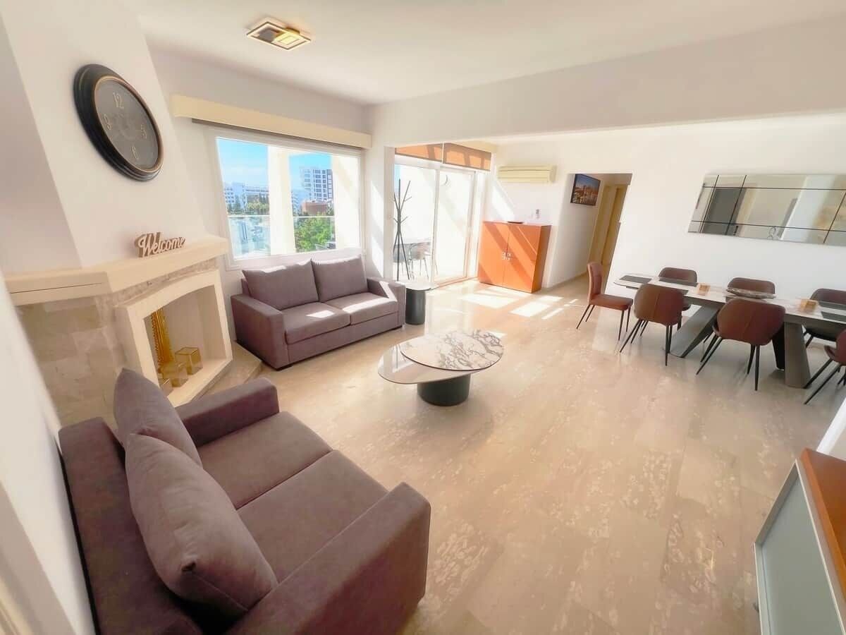A modern living room with a sofa, coffee table, and dining area with chairs.