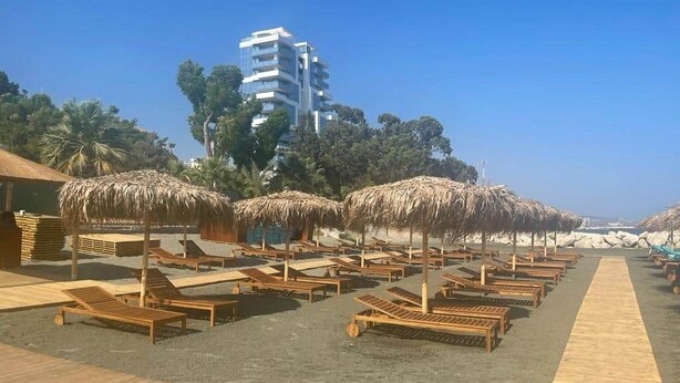 A beachside hotel with wooden loungers, thatched umbrellas, and a clear view of the ocean.