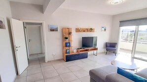 Una sala de estar moderna con sofá, televisor y mueble de entretenimiento.