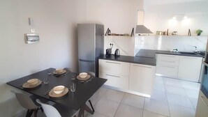 Una cocina moderna con comedor, que incluye una isla central, electrodomésticos integrados y una lámpara contemporánea.