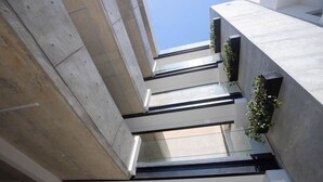 A modern architectural structure with concrete pillars, glass railings, and greenery. - Bridge House 202-2BR Modern Apt. (Limassol)