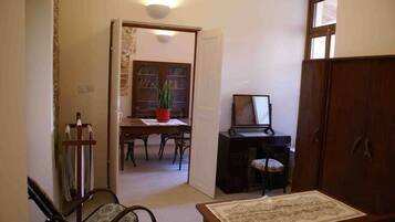 A room with a dining table, chairs, a bookshelf, a desk with a chair, and a cabinet.