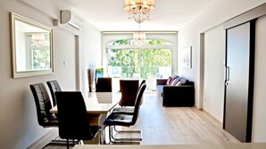 Uma zona de refeições moderna com uma mesa, cadeiras, um candelabro e vista através de uma janela ampla.