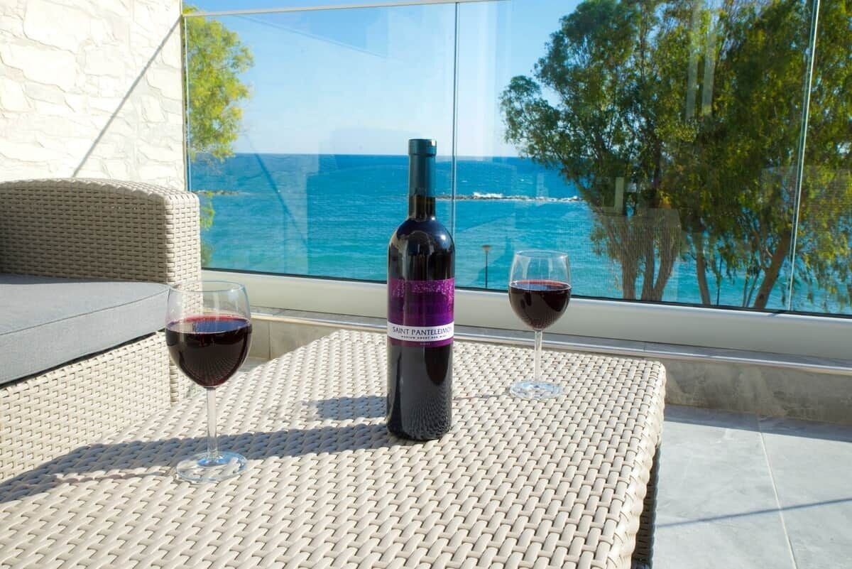 Uma garrafa de vinho e dois copos sobre uma mesa, com vista para o oceano.