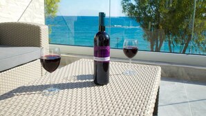 Uma garrafa de vinho e dois copos sobre uma mesa, com vista para o oceano.