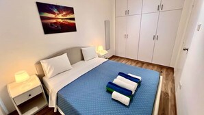 Un dormitorio con cama, mesitas de noche, un armario y un cuadro en la pared.