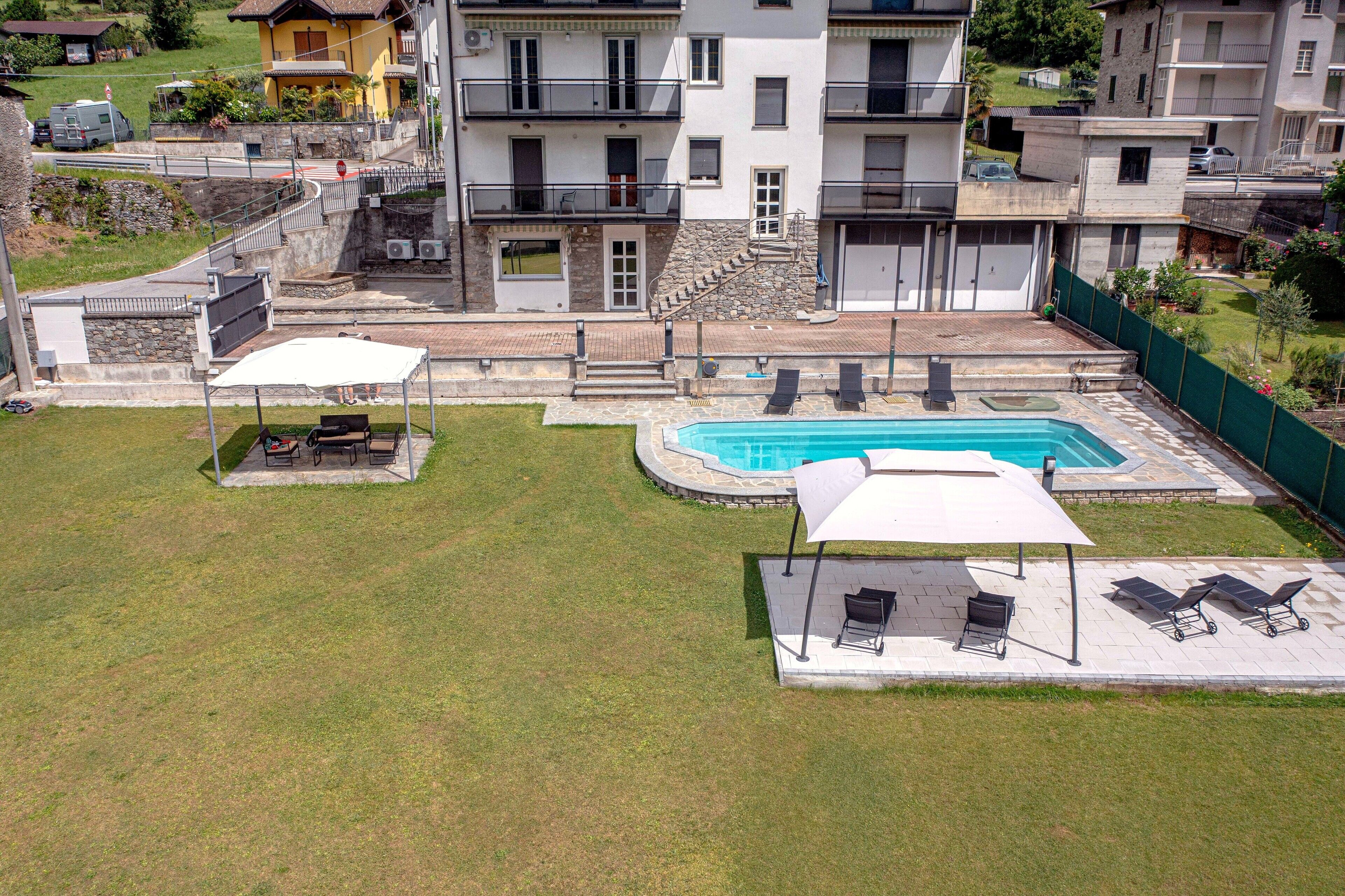 A residential building with a swimming pool, outdoor seating, and a stone staircase.