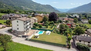 A residential area with houses, a swimming pool, and a mountain backdrop.