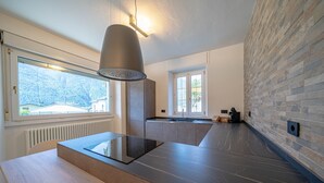 A modern kitchen with a built-in stove, a large window, and a stone wall.