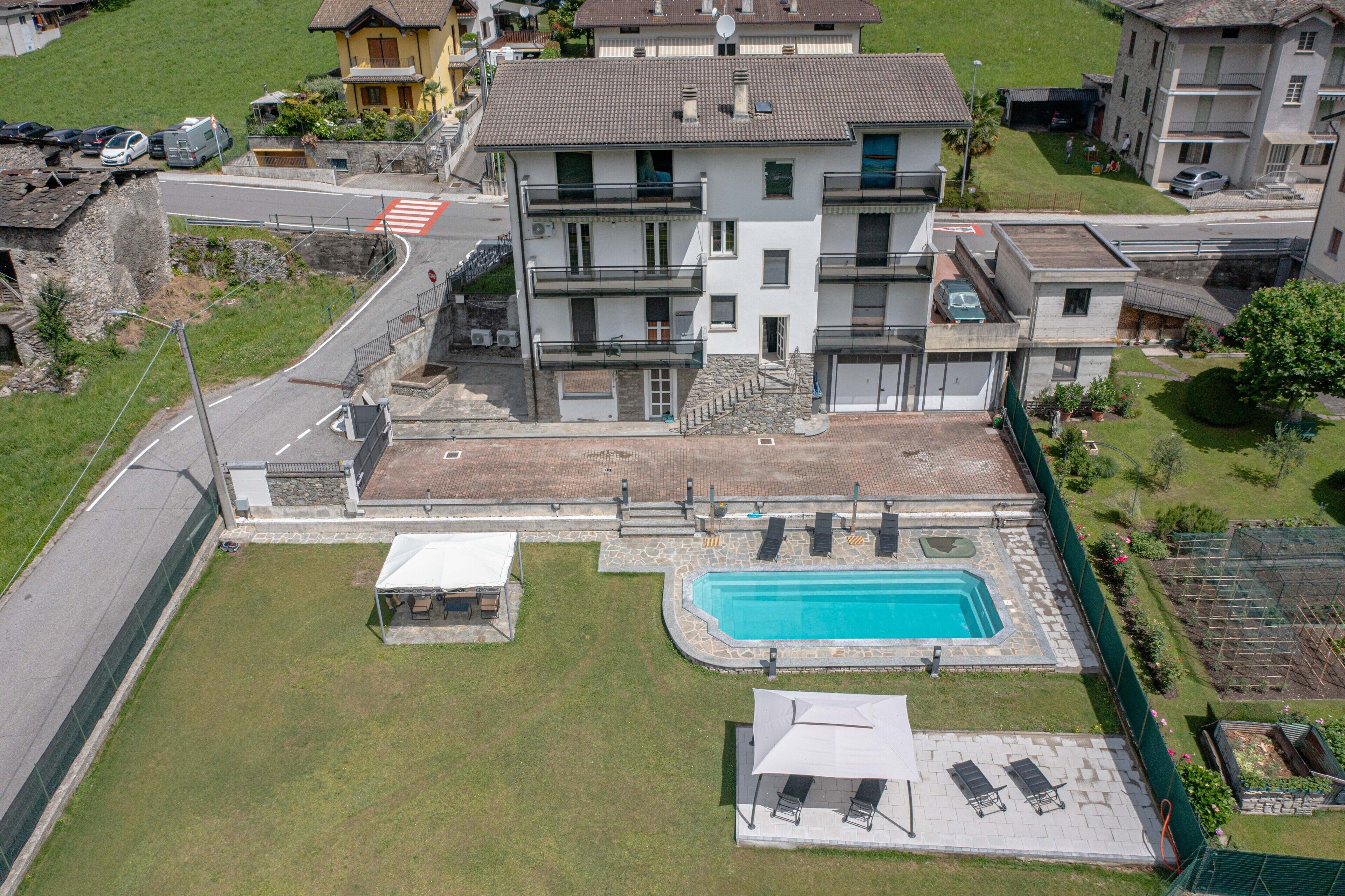 A residential building with a swimming pool, a covered patio, and a street view.