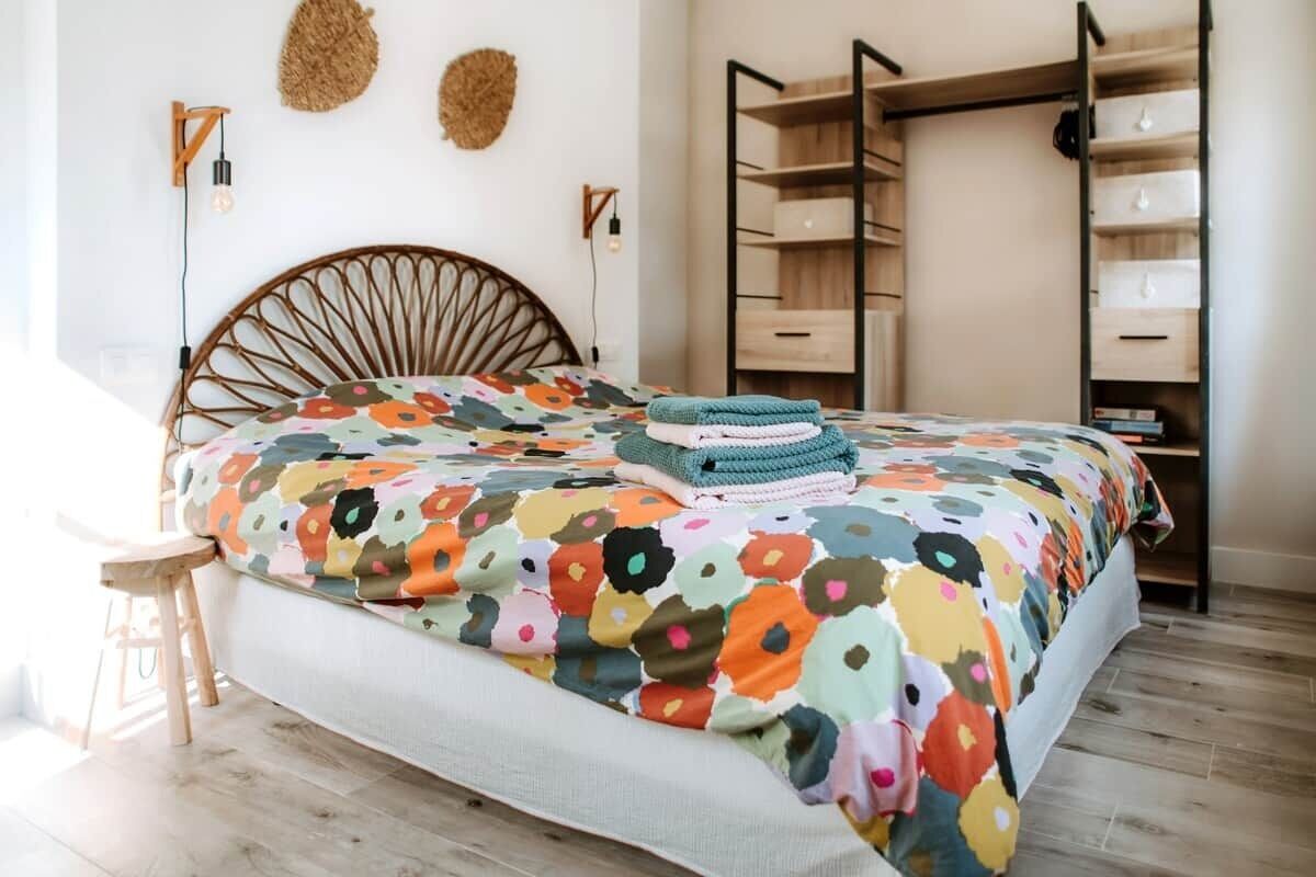 Een slaapkamer met een bed, een houten hoofdbord, een wandplank en een inbouwkast.