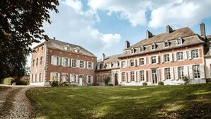 Ein großes, historisches Gebäude mit Innenhof, zahlreichen Fenstern und einem Kopfsteinpflasterweg.