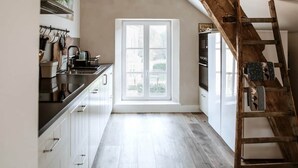 Eine Küche mit Fenster, einer Holzleiter und modernen Geräten.