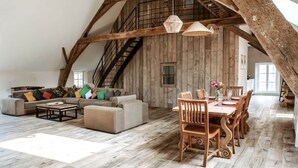 Ein großzügiges Loft mit freiliegenden Holzbalken, einem Essbereich und einer Treppe.