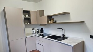 Eine kleine Küche mit einem schwarzen Spülbecken, weißen Schränken und Holzboden.