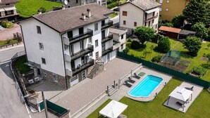 Ein mehrgeschossiges Wohnhaus mit Swimmingpool, Außenbereich und überdachter Terrasse.