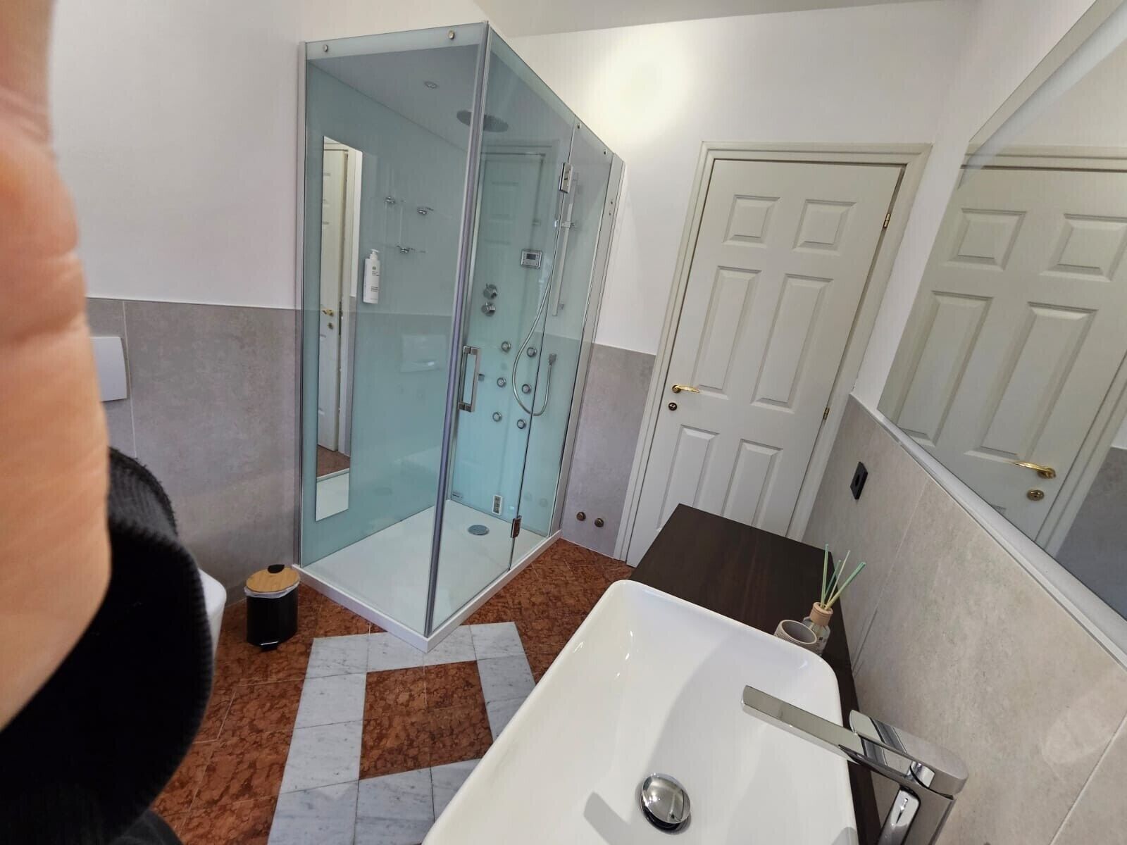 Une salle de bain avec une douche à parois de verre, un lavabo blanc et une porte.