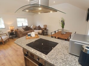 A modern kitchen with a granite countertop, built-in oven, and a stainless steel refrigerator.