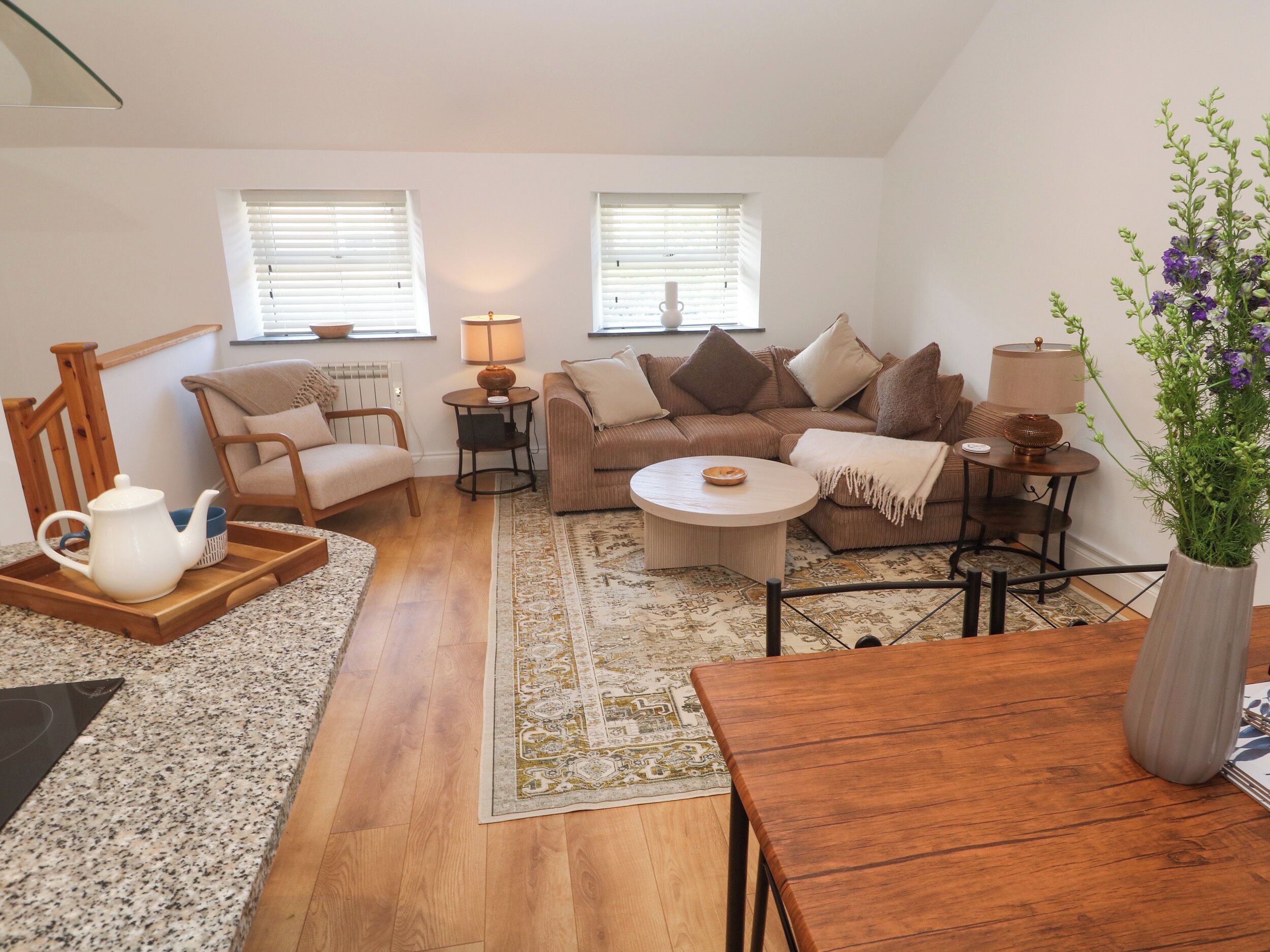 A cozy living room with a sofa, armchairs, a coffee table, and a wooden side table.