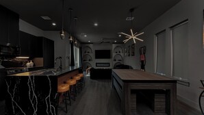 Een moderne keuken met een marmeren kookeiland, barstoelen en een eettafel.