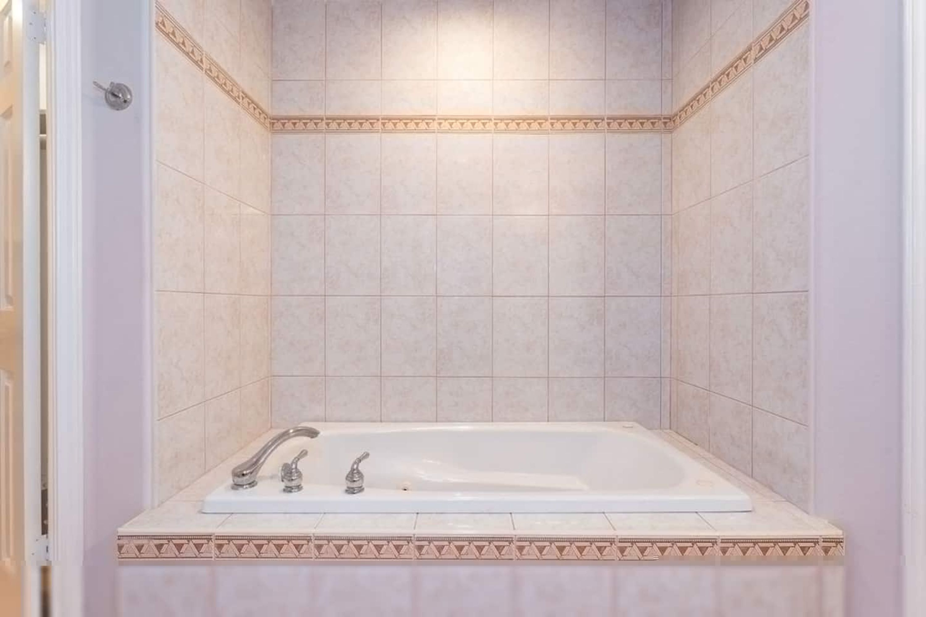 A bathroom with a bathtub, tiled walls, and a decorative border.