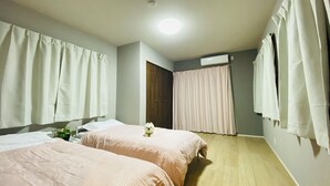 Une chambre d’hôtel avec deux lits, un plancher en bois, un luminaire au plafond et un appareil de climatisation.