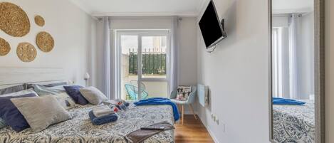 A bedroom with a bed, a TV, a window, and a balcony.