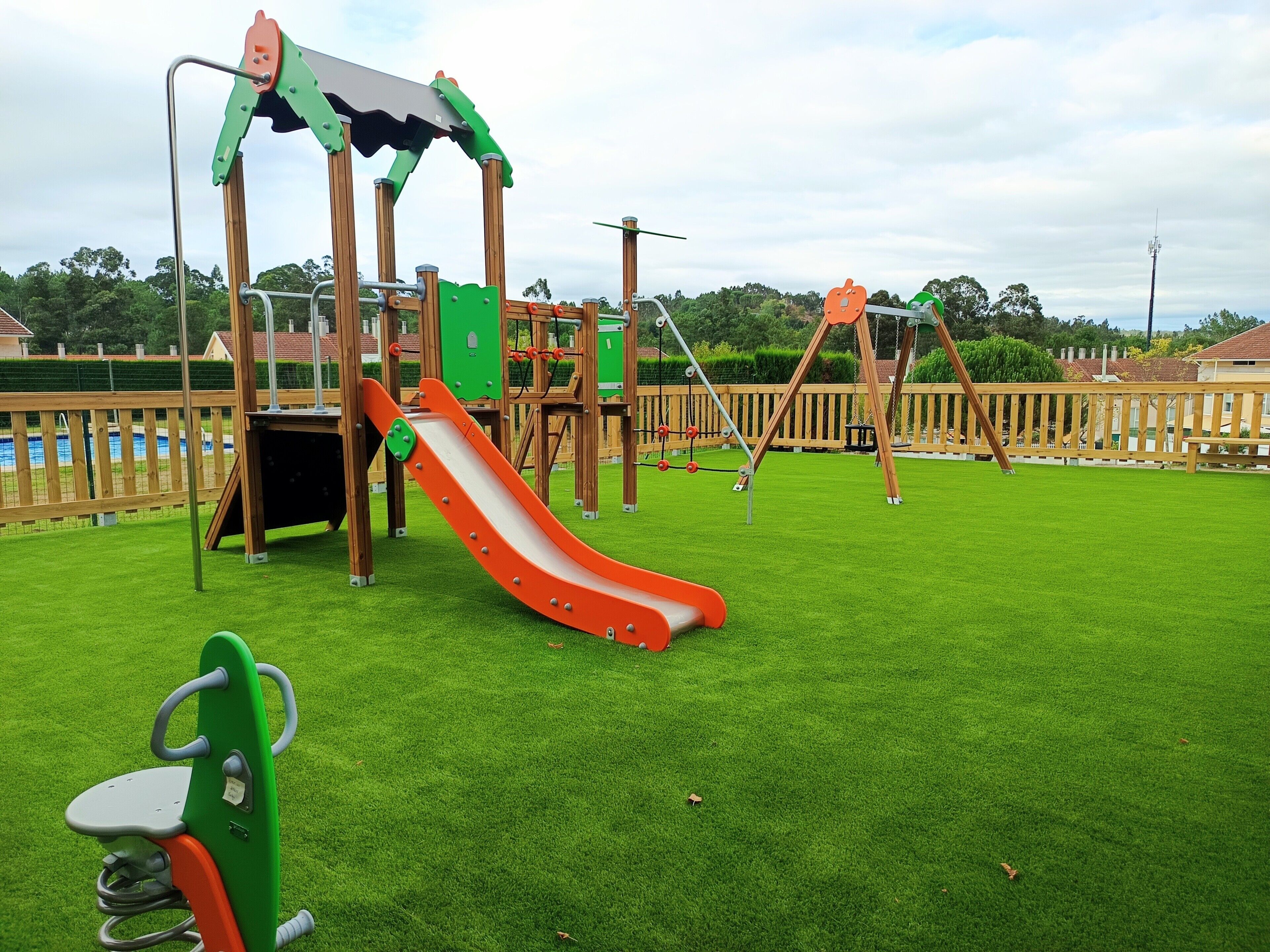 Un parque infantil con tobogán, columpios y una estructura para escalar.
