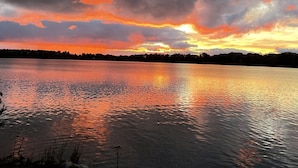 Un lago tranquilo reflejando un atardecer con nubes en el cielo.