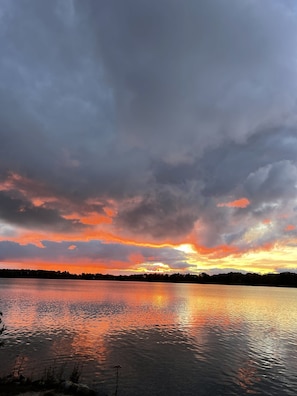Un lac paisible où se reflète un coucher de soleil, avec des nuages dans le ciel.