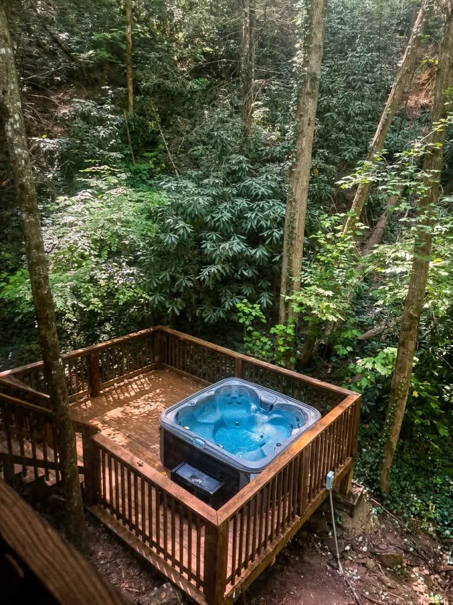 Un jacuzzi en una terraza de madera rodeado de un bosque denso.